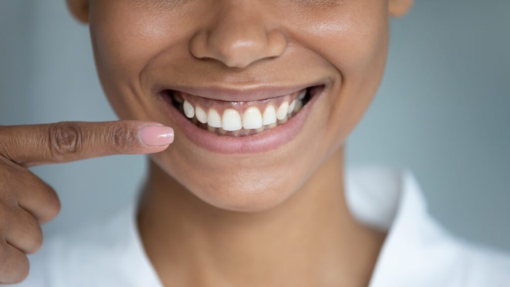 woman with healthy gums pointing to her smile