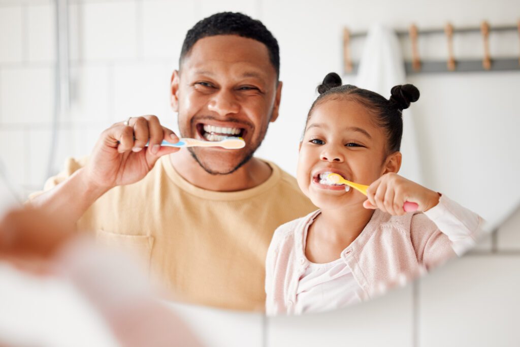 father and daughter brushing their teeth