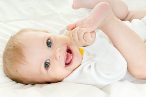 baby playing with feet smiling