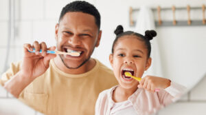 Father and daughter brushing their teeth